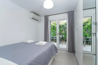 a white bedroom with a bed and a balcony at Maria's Garden in Athens
