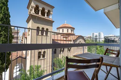 a balcony with a wooden chair and a building at Athens Central Charm by ΜΡS in Athens
