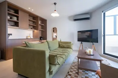 a living room with a green couch and a tv at Athens Central Skyline Studio by ΜΡS in Athens