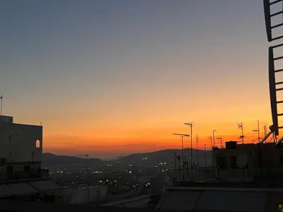 a sunset over a city with buildings and street lights at Athenian Loft with urban view! in Athens