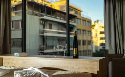 a bottle of wine and two glasses on a table with a window at Bliss Luxury Apartments in Athens
