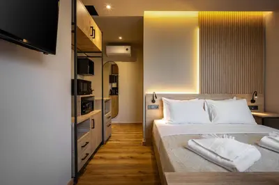 a bedroom with a bed with white pillows and a television at Bliss Luxury Apartments in Athens