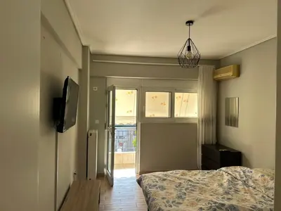 a bedroom with a bed and a tv and a window at Athens Cozy Apartment in Athens