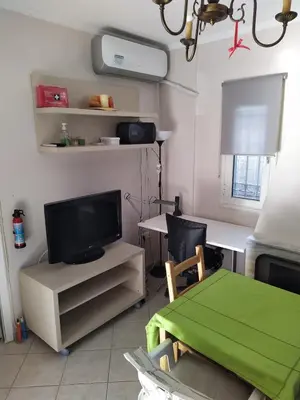 a living room with a television and a table with a green blanket at Private Little House in Lagonisi in Áyios Nikólaos
