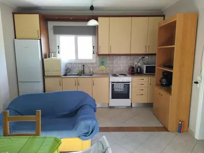 a kitchen with wooden cabinets and a blue blanket in it at Private Little House in Lagonisi in Áyios Nikólaos