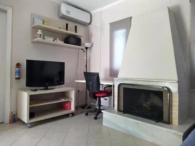 a living room with a television and a fireplace at Private Little House in Lagonisi in Áyios Nikólaos