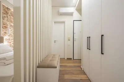 a bedroom with white walls and a bench in a room at Stone house in Athens in Athens