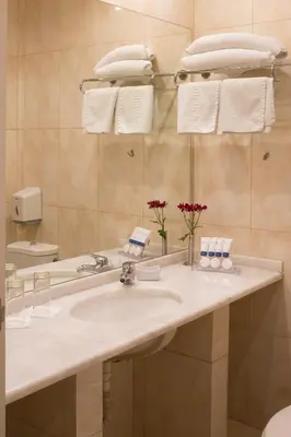 a bathroom with a sink and a mirror and towels at Blue Sea Hotel Alimos in Athens