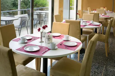 a table and chairs in a restaurant with a table and chairs at Blue Sea Hotel Alimos in Athens