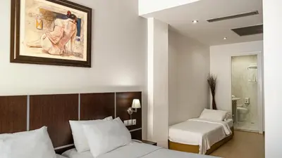 a bedroom with two beds and a painting on the wall at Blue Sea Hotel Alimos in Athens