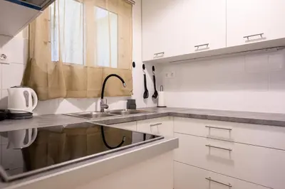a white kitchen with a sink and a window at Patision cinema apartment in Athens