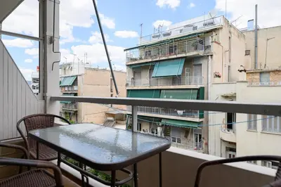 a table on a balcony with a view of a building at Patision cinema apartment in Athens
