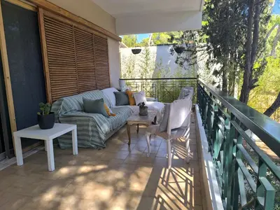 a balcony with a couch and a table and chairs at Silver Paradeisi Apartment in Palaiá Fókaia