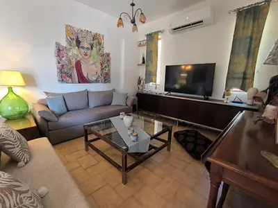 a living room with a couch and a tv at Silver Paradeisi Apartment in Palaiá Fókaia