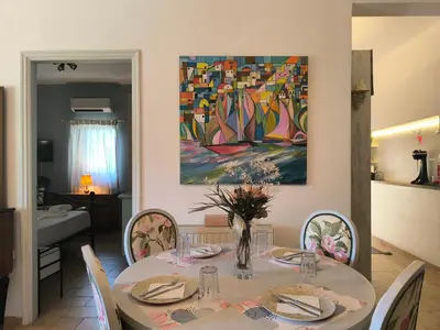a dining room with a table and a painting on the wall at Silver Paradeisi Apartment in Palaiá Fókaia