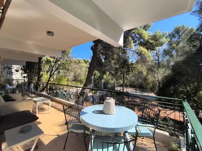 a balcony with a table and chairs and trees at Silver Paradeisi Apartment in Palaiá Fókaia