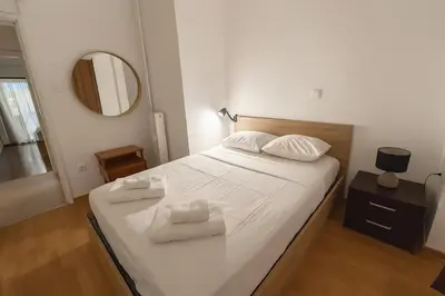 a bedroom with a bed with white sheets and a mirror at Dafni 2Bdrm apartment in Neapoli by ΜΡS in Athens