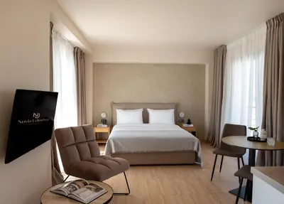 a hotel room with a bed and a chair at Nuvia UrbanStay Piraeus Apartments in Piraeus