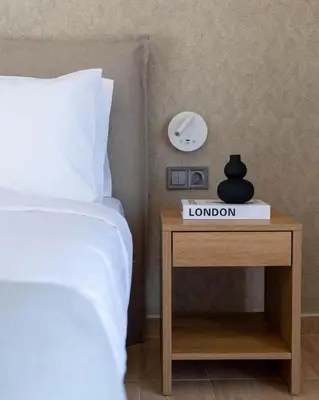 a bed and a nightstand with a alarm clock on it at Nuvia UrbanStay Piraeus Apartments in Piraeus