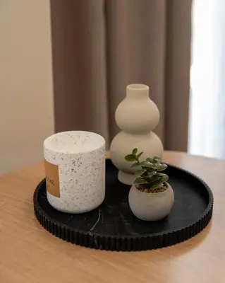 a table with two white vases on a black plate at Nuvia UrbanStay Piraeus Apartments in Piraeus