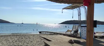 a beach with people in the water and an umbrella at Αριάδνη στούντιο με θέα in Anavissos