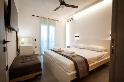 a white bedroom with a bed and a ceiling fan at Nicolas Villa in Anavissos