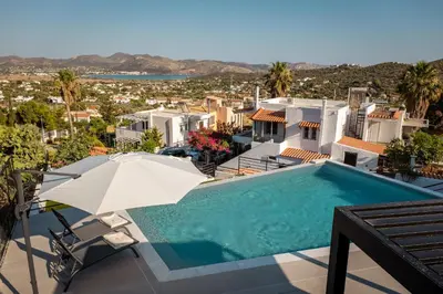 a swimming pool with an umbrella and a house at Nicolas Villa in Anavissos