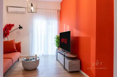 a living room with an orange wall and a tv at Duplex in Piraeus' Best Street 2Bath w-FreeParking in Piraeus