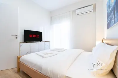a bedroom with a bed with a tv on the wall at Duplex in Piraeus' Best Street 2Bath w-FreeParking in Piraeus