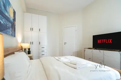 a white bedroom with a bed and a tv at Duplex in Piraeus' Best Street 2Bath w-FreeParking in Piraeus