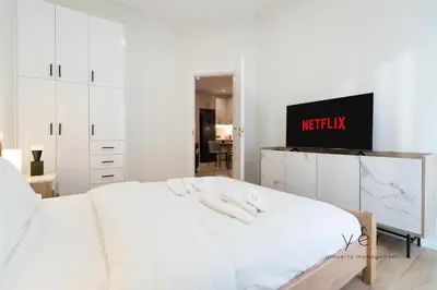 a white bedroom with a bed and a tv at Duplex in Piraeus' Best Street 2Bath w-FreeParking in Piraeus