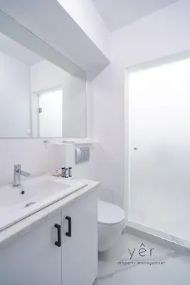 a white bathroom with a sink and a toilet at Duplex in Piraeus' Best Street 2Bath w-FreeParking in Piraeus