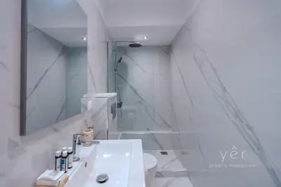 a white bathroom with a sink and a mirror at Duplex in Piraeus' Best Street 2Bath w-FreeParking in Piraeus