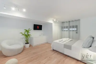 a white bedroom with a large bed and a chair at Seaside Loft Near Piraeus Port at Freatida Beach in Piraeus