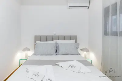 a white bedroom with a bed with white sheets and pillows at Seaside Loft Near Piraeus Port at Freatida Beach in Piraeus