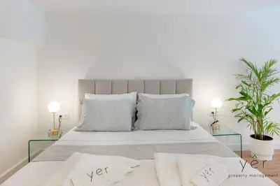 a white bedroom with a large bed with two pillows at Stylish Loft at Pasalimani 10min to Freatida Beach in Piraeus