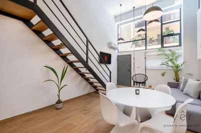 a living room with a white table and white chairs at Stylish Loft at Pasalimani 10min to Freatida Beach in Piraeus
