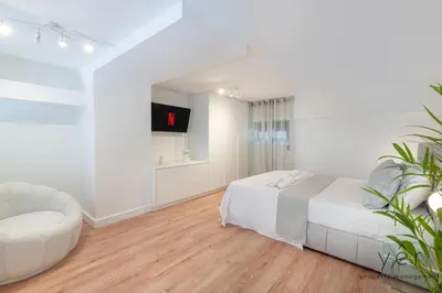 a white bedroom with a bed and a chair at Stylish Loft at Pasalimani 10min to Freatida Beach in Piraeus