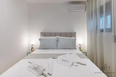 a white bed with white sheets and towels on it at Stylish Loft at Pasalimani 10min to Freatida Beach in Piraeus