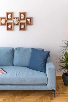 a blue couch in a living room with pictures on the wall at Coastal Charm at Pasalimani - Steps from Port&Beach in Piraeus
