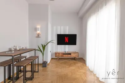 a living room with a table and a tv on a wall at Coastal Charm at Pasalimani - Steps from Port&Beach in Piraeus