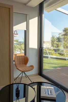 a chair and tables in a room with a window at Athens Riviera Suite in Athens