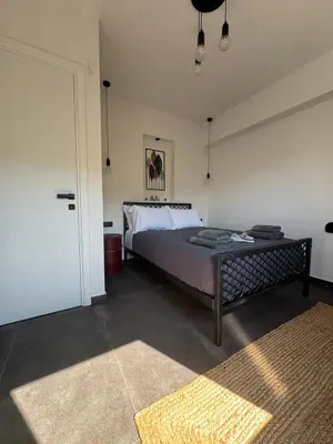 a bedroom with a bed and a door with a rug at Escape Suites - Sea View in Porto Rafti