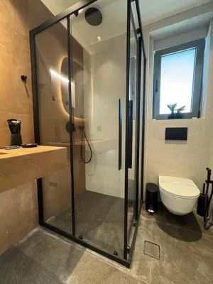 a bathroom with a shower and a toilet and a window at Escape Suites - Sea View in Porto Rafti