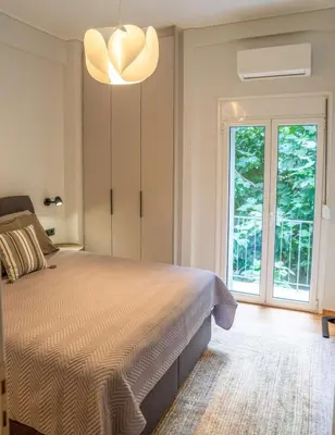 a bedroom with a bed and a large window at Philosykos Suite in Athens