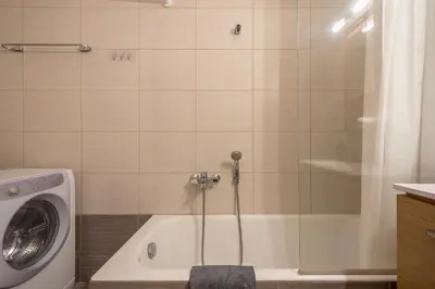 a bathroom with a washing machine next to a tub at Cozy 2 bedroom flat near Gazi in Athens