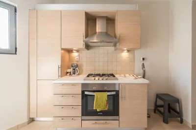 a kitchen with wooden cabinets and a stove top oven at Cozy 2 bedroom flat near Gazi in Athens