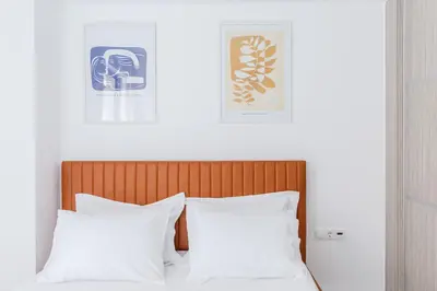 a bed with two white pillows and two pictures on the wall at Noon Smart Residences in Athens