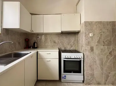 a small kitchen with white cabinets and a sink at 2 bedroom near Dafni metro in Athens