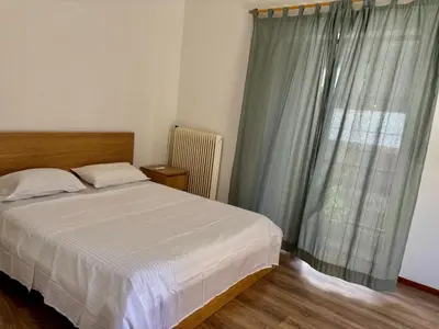 a bedroom with a bed and a large window at 2 bedroom near Dafni metro in Athens